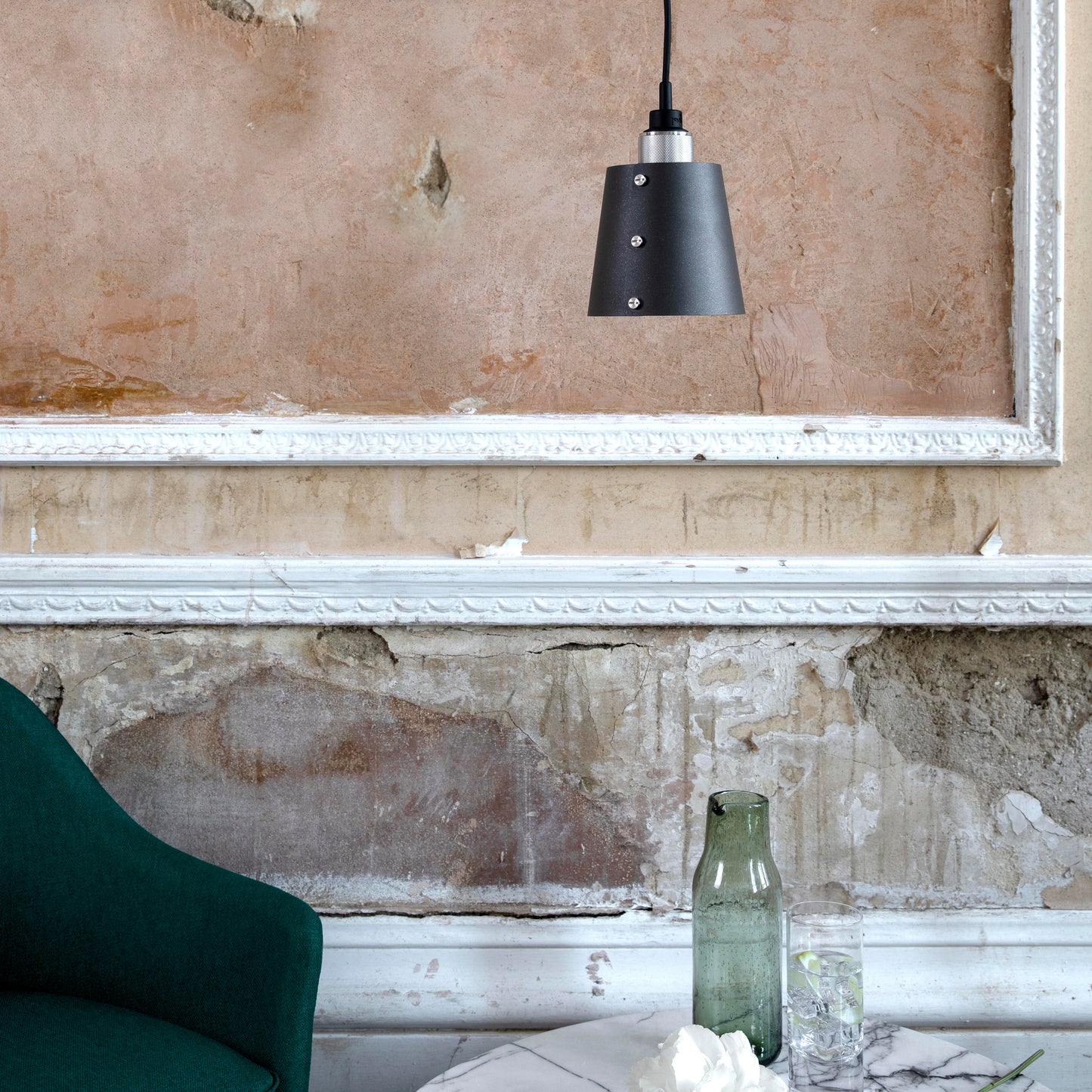 Hooked 1.0 Small Pendant Light / Graphite Steel, hanging from ceiling in setting with background.