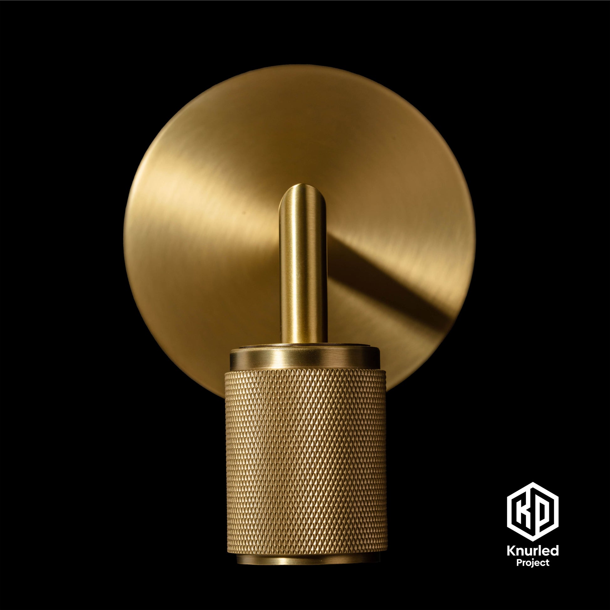 Brass wall light zoomed in to show diamond cut and knurled finish on a black background