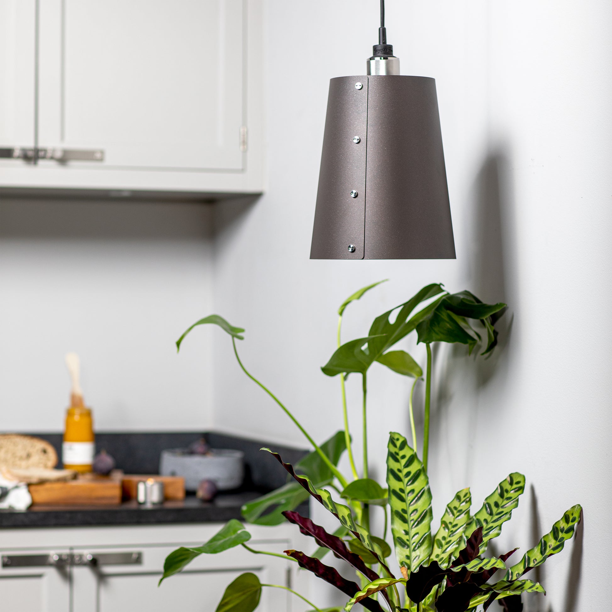 Hooked 1.0 Large Pendant Light / Graphite steel, hanging from ceiling in kitchen setting.