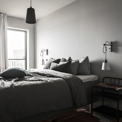 Hooked 1.0 Large Pendant Light / Graphite Smoked bronze, hanging from ceiling above bed in bedroom setting.