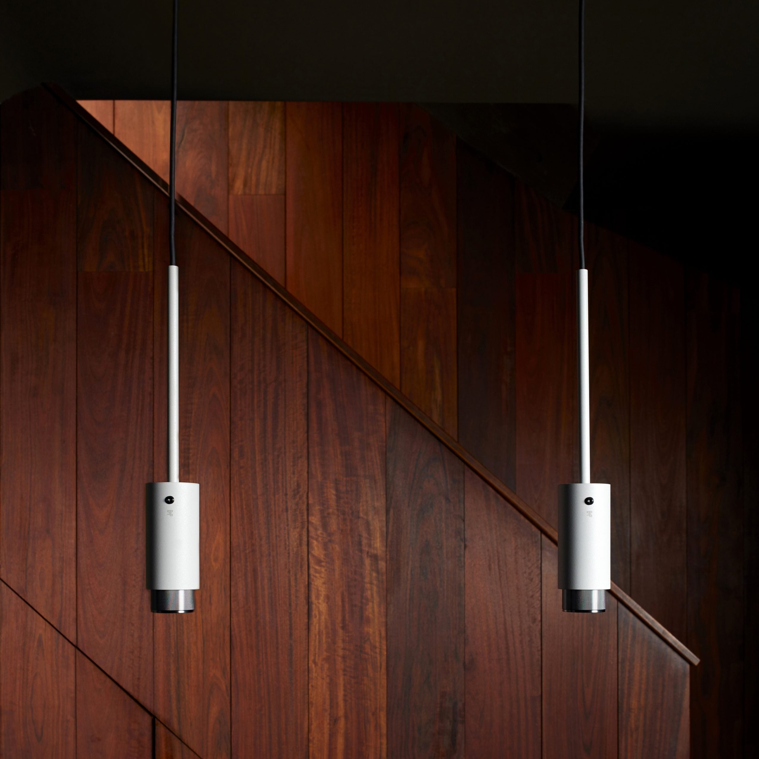 Exhaust Pendant Light / Linear / Stone Brass, pendants hanging from ceiling in setting with background.