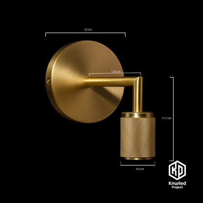 Brass wall light at an angle with product measurements on a black background